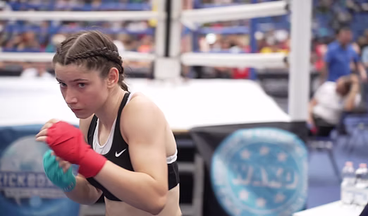 Young female kickboxing athlete warming up beside the competition area