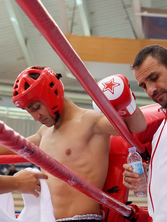 Coach giving advice to a kickboxing athlete between rounds