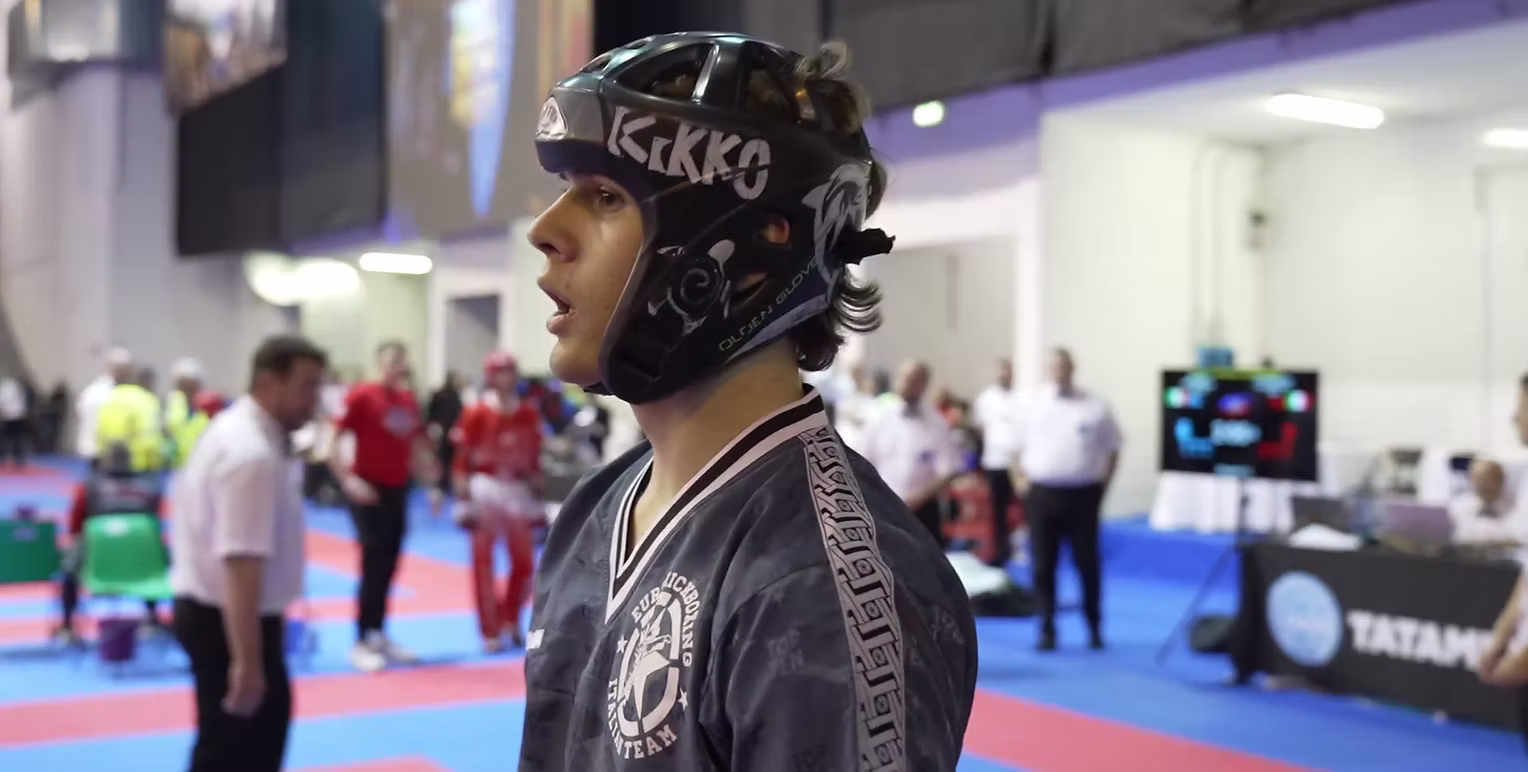 Young kickboxing competitor wearing protective headgear at a competition event